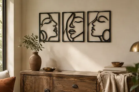 Trois éléments muraux noirs en MDF découpé, formant des visages stylisés sur un mur ivoire.